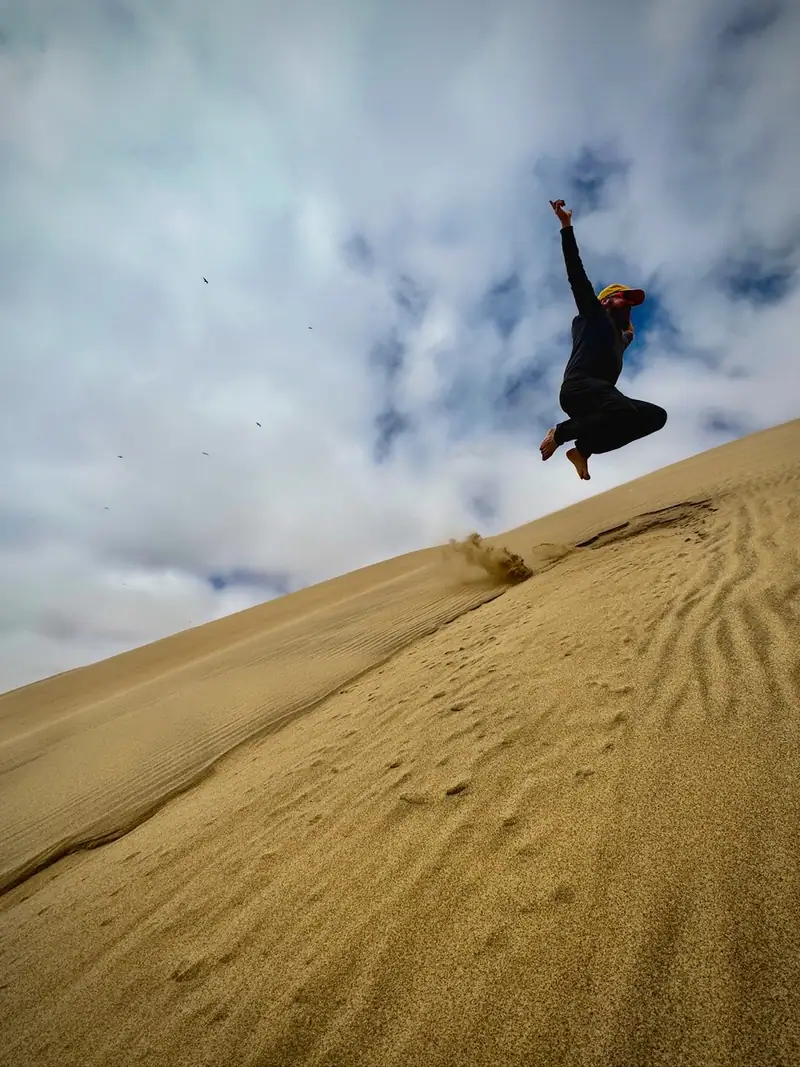 Jumping while climbing barefoot up a dune of the Namib Desert