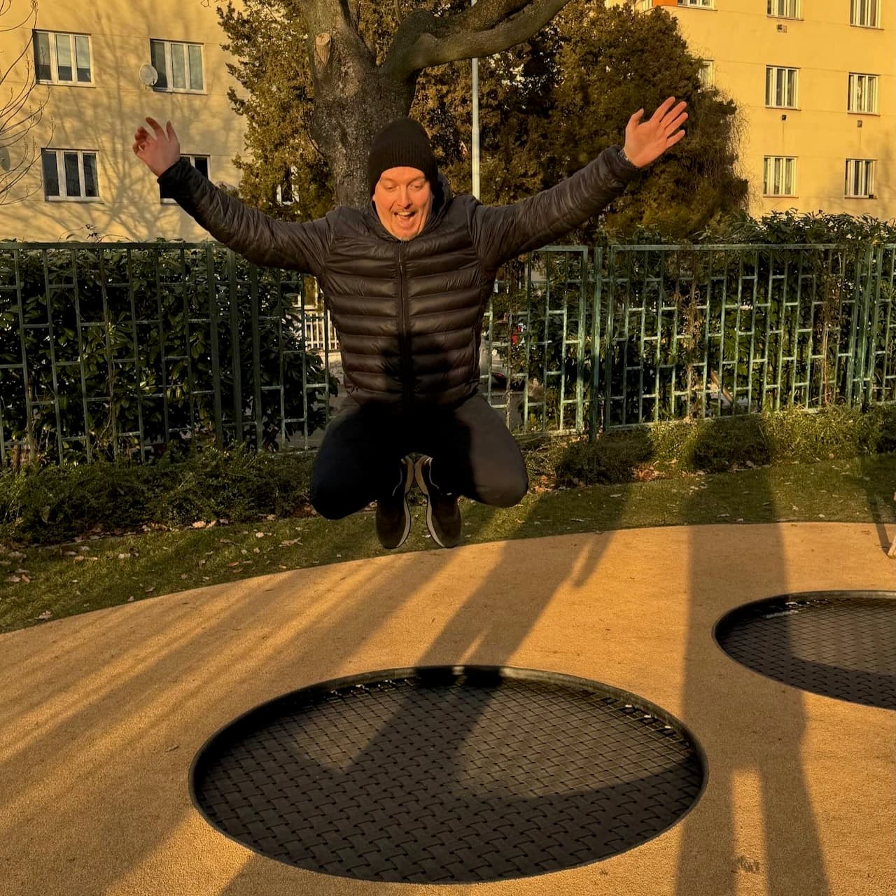 Sylvain bouncing on a trampoline set into the ground of a Prague playground